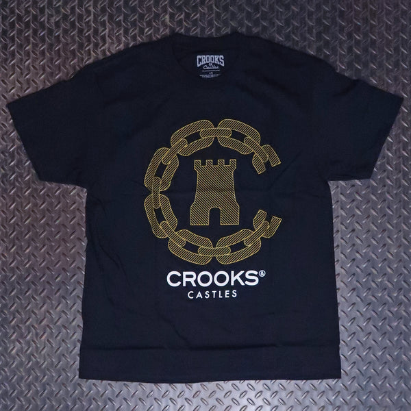 A black short-sleeve t-shirt laid flat on a textured diamond plate background, featuring a large gold chain-link castle graphic and the text 'CROOKS CASTLES' printed on the front. Crooks & Castles Streak T-Shirt Black 5Z57046