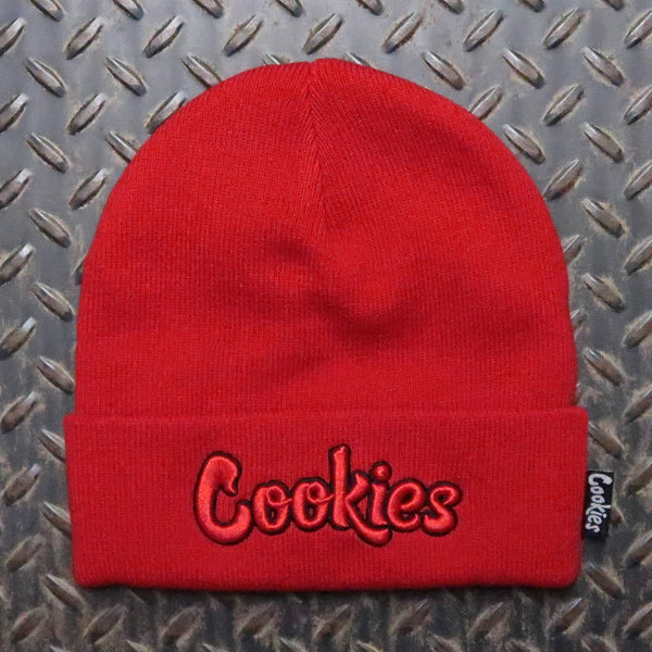A bright red knit beanie hat with the word 'Cookies' embroidered in red and black on the front cuff, shown against a dark diamond plate metal background. Cookies Original Logo Outline Knit Beanie Red Black CM253XKB04
