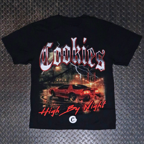 A black short-sleeve graphic t-shirt laid flat on a textured gray diamond plate background. The shirt features a large front print with the word 'Cookies' in a stylized white and red font, a red sports car drifting at night with lightning in the background, and the phrase 'High By Night' in red script below. Cookies High By Night Premium T-Shirt Black CM263TSP21