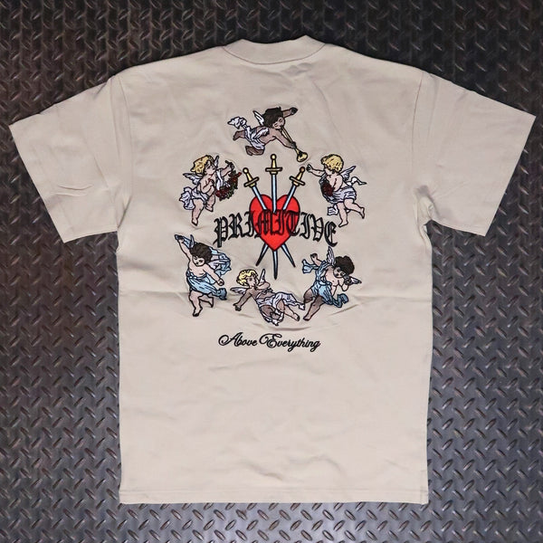 A sand colored short-sleeve t-shirt laid flat on a dark textured diamond plate background, featuring a large graphic print on the back with cherubs, a red heart, crossed swords, the word 'PRIMITIVE', and 'Above Everything' written below. Primitive Triumph Heavyweight Knit T-Shirt Sand PA425376
