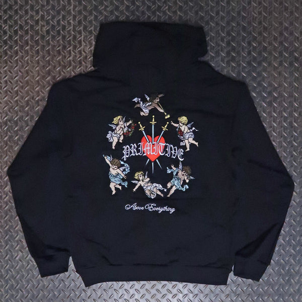 A black hoodie laid flat on a textured gray diamond plate background, showing the back graphic. The design features a red cross with a white starburst, the word 'PRIMITIVE' in white gothic lettering, a circle of cherubs, and 'Above Something' in white script below. Primitive Triumph Heavyweight Pullover Hoodie Black PA425272